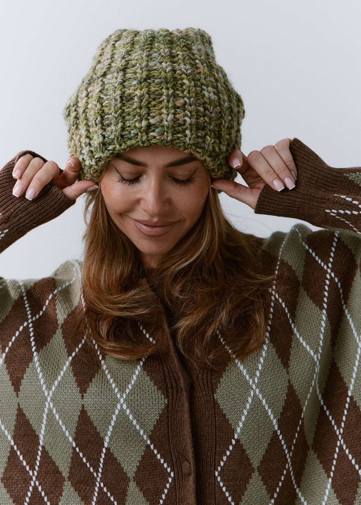 BRIKOLY Apple green oversized knit beanie worn by a model looking down and adjusting the brim.