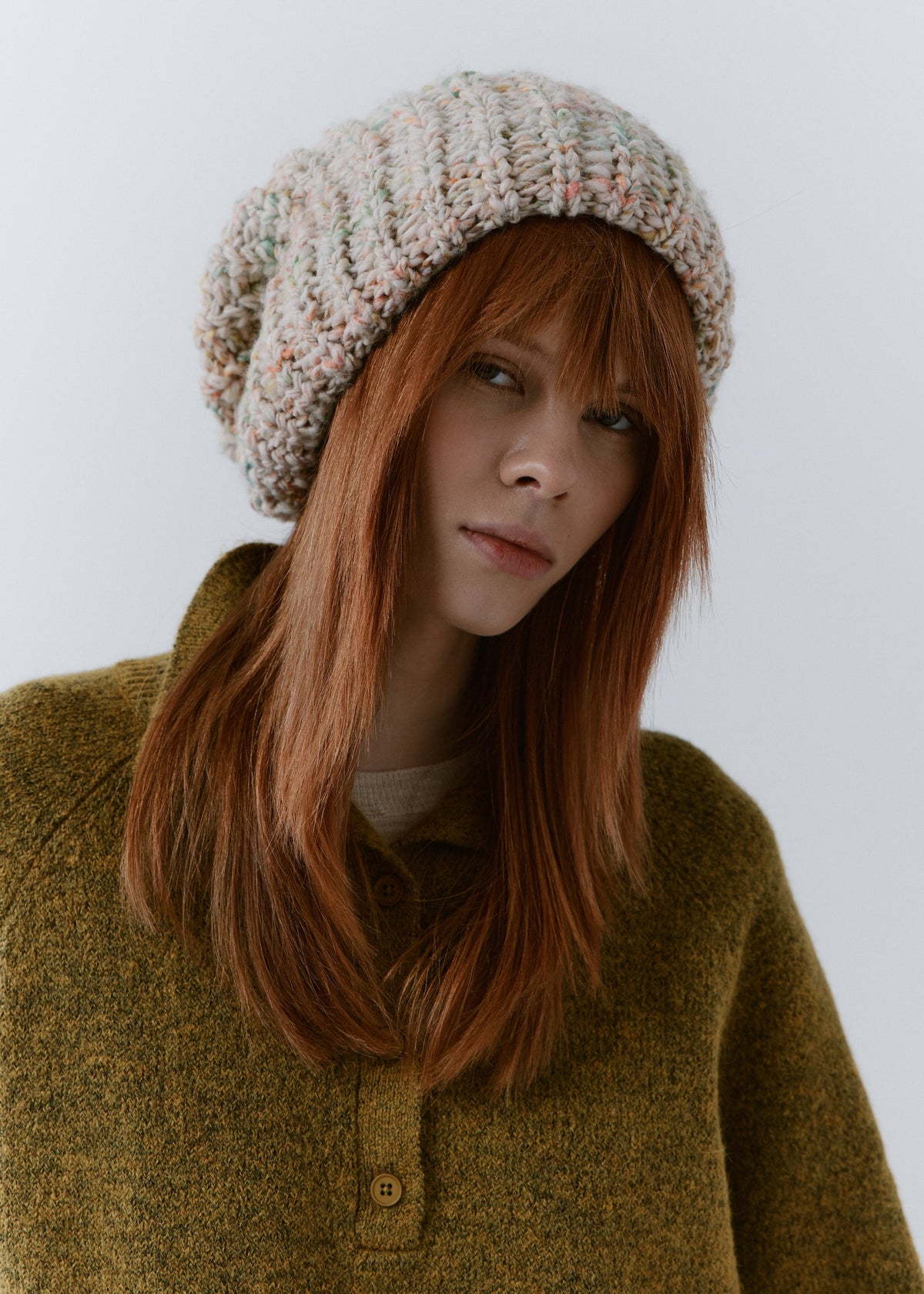 BRIKOLY Snowdrop pale multicolor oversized knit beanie worn by a model in a front view over an olive cardigan.