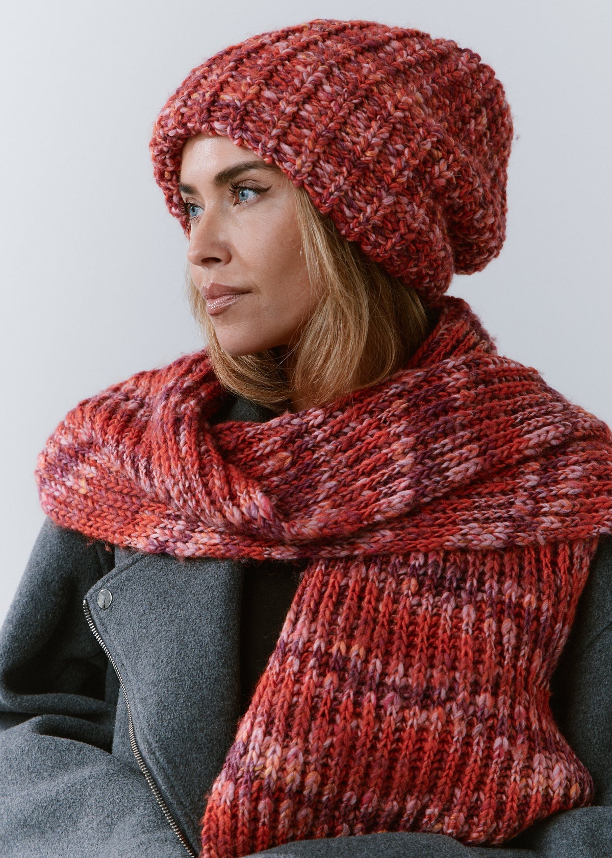 BRIKOLY Red oversized multicolor knit beanie worn by a model with a matching scarf wrapped around her shoulders.