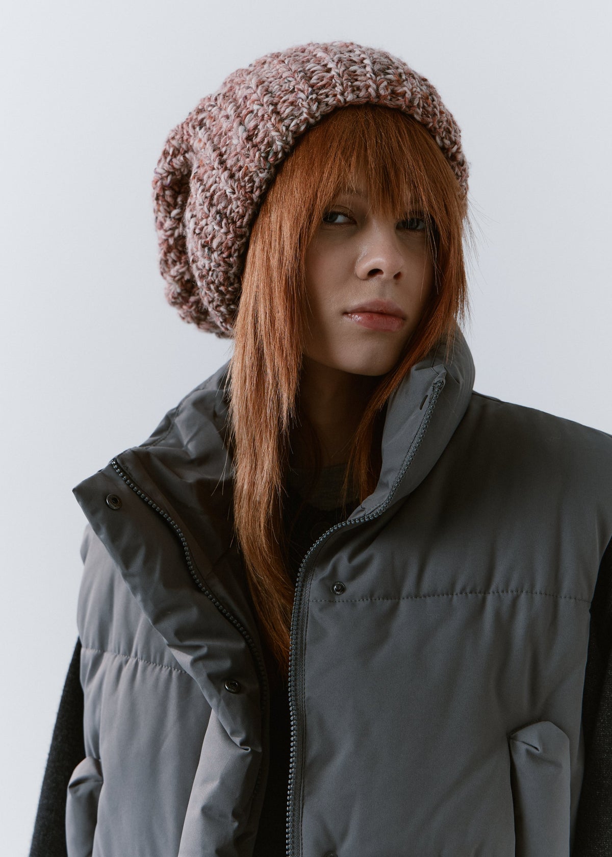 BRIKOLY Rose oversized multicolor knit beanie worn by a model in a front view over a gray padded vest.