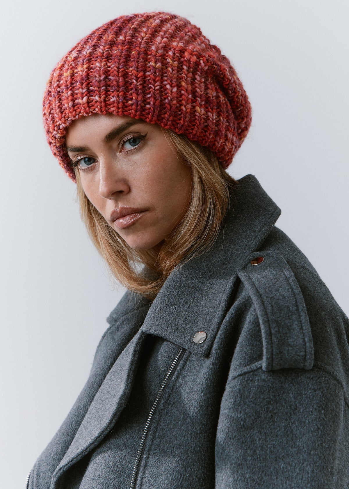 London Red knit beanie: Side portrait in a gray coat