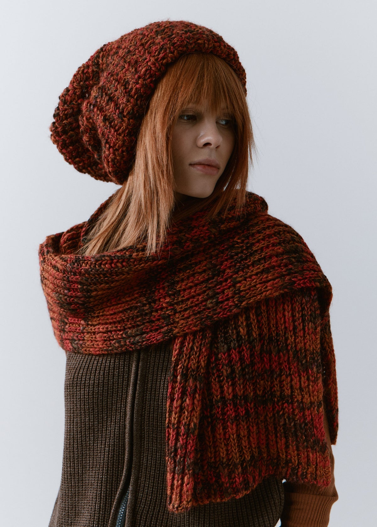 BRIKOLY Brown ribbed knit scarf in red-brown multicolor yarn, wrapped loosely around a model's neck in a front view.