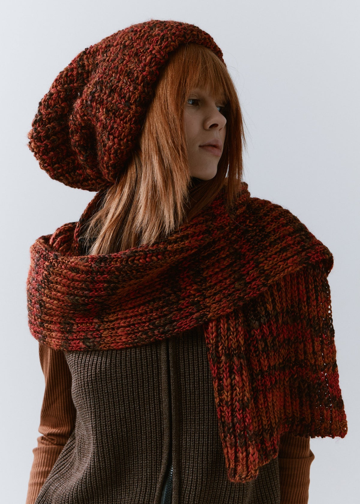BRIKOLY Brown ribbed knit scarf in red-brown multicolor yarn, draped across a model's shoulders in a three-quarter view.