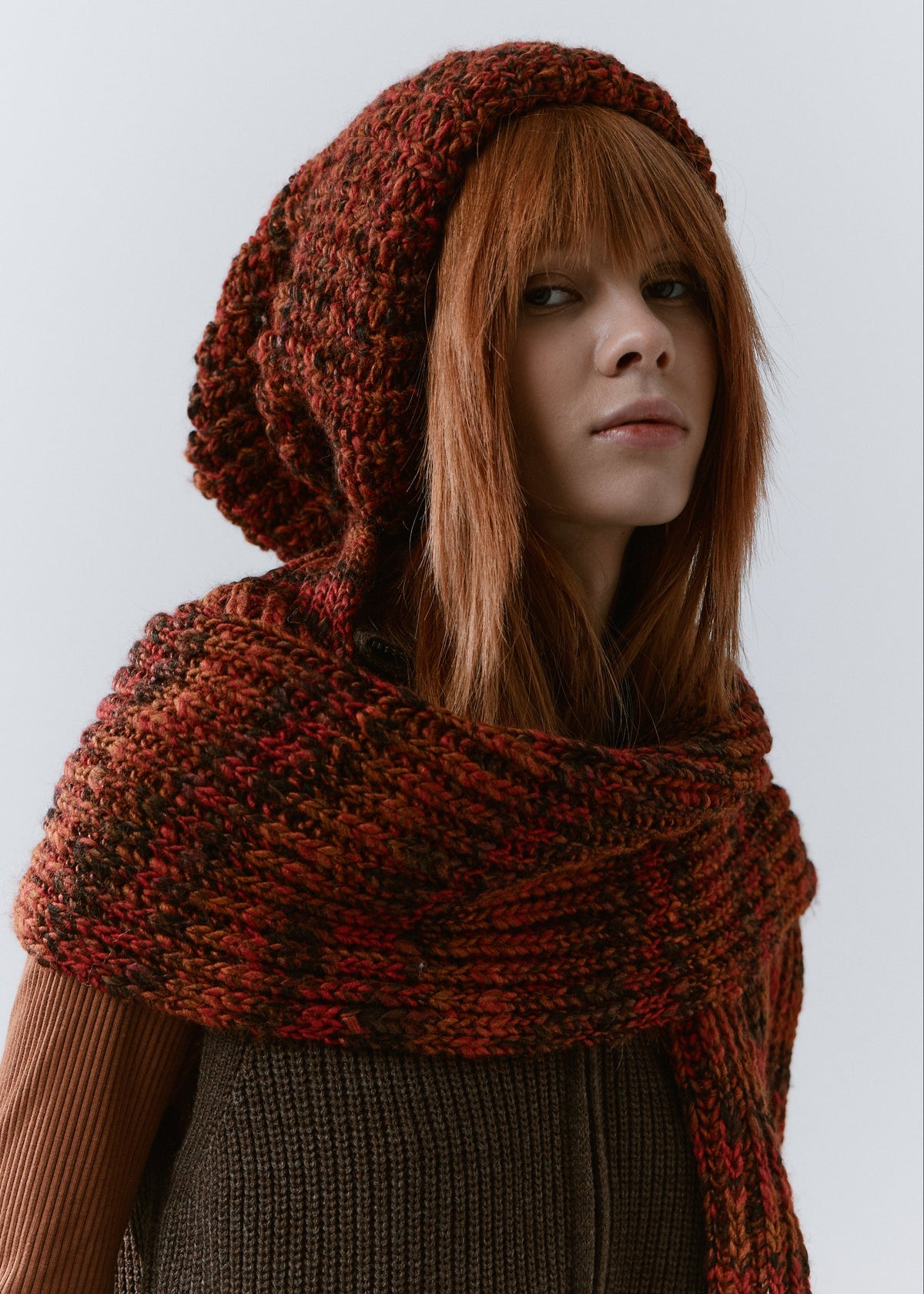 BRIKOLY Brown ribbed knit scarf in red-brown multicolor yarn, shown close up across a model's upper chest and shoulders.