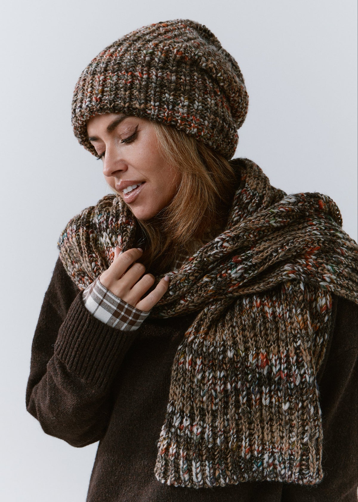 London Multicolor knit beanie: Looking-down portrait holding matching scarf, sold separately