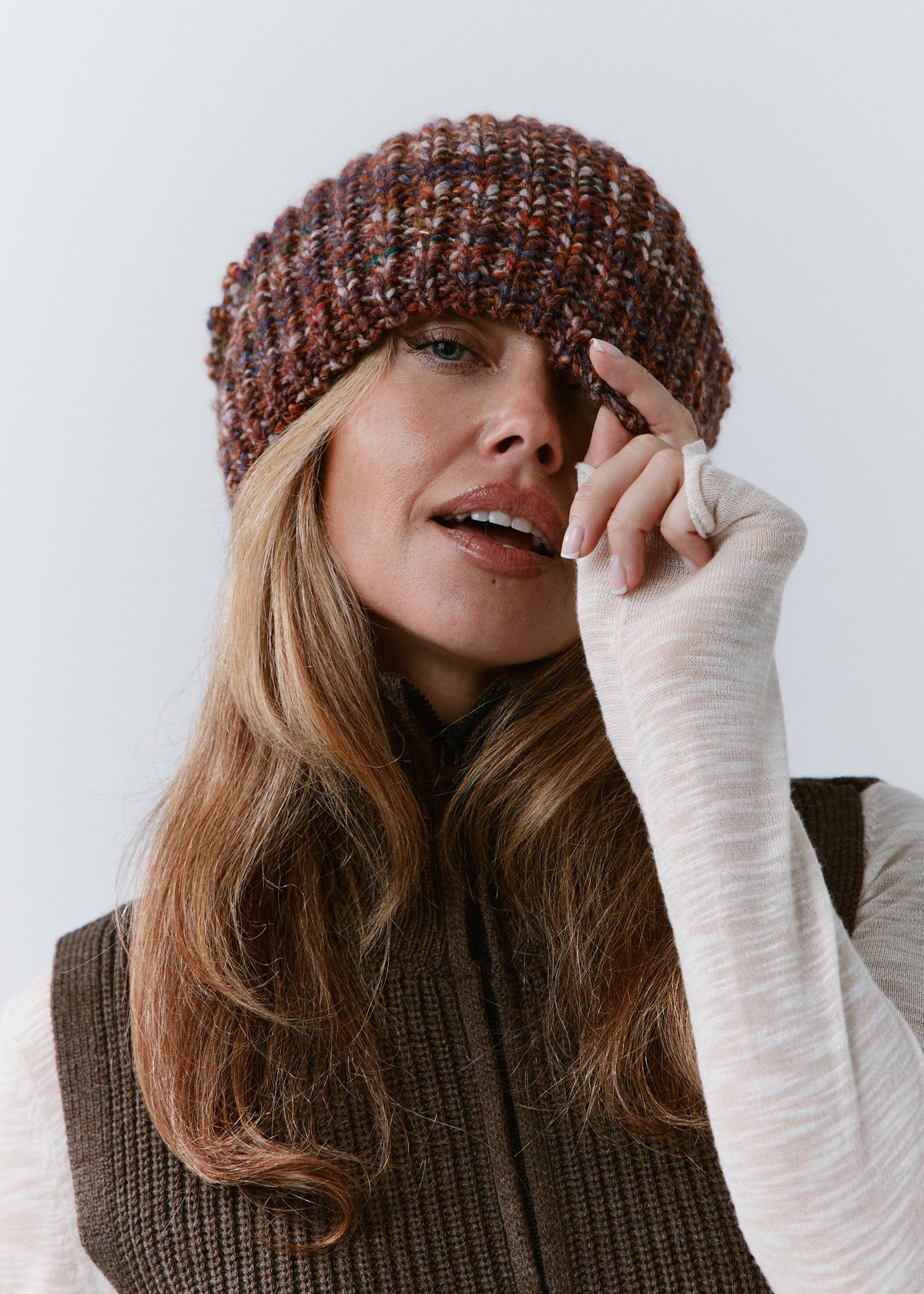 London Eggplant knit beanie: Close-up with a hand at the brim