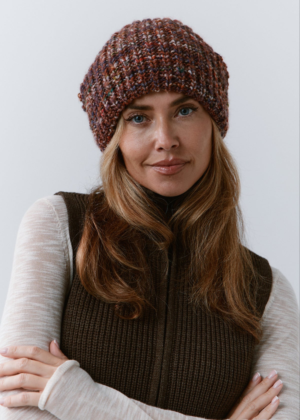 London Eggplant knit beanie: Seated front portrait with folded arms