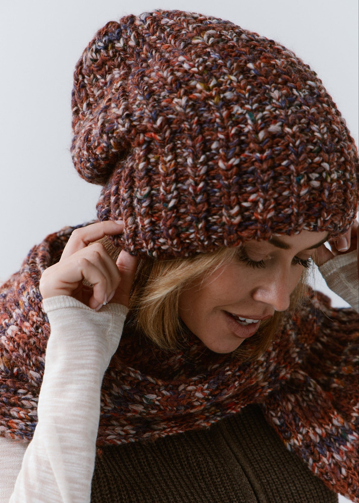 BRIKOLY Eggplant oversized multicolor knit beanie worn by a model looking down and adjusting the brim.