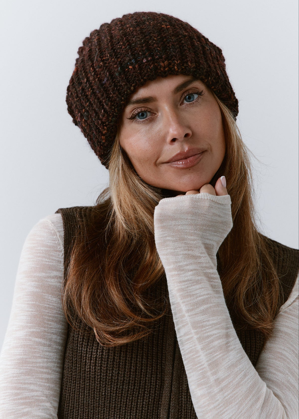 London Burgundy and Black knit beanie: Front portrait with a hand beneath the chin