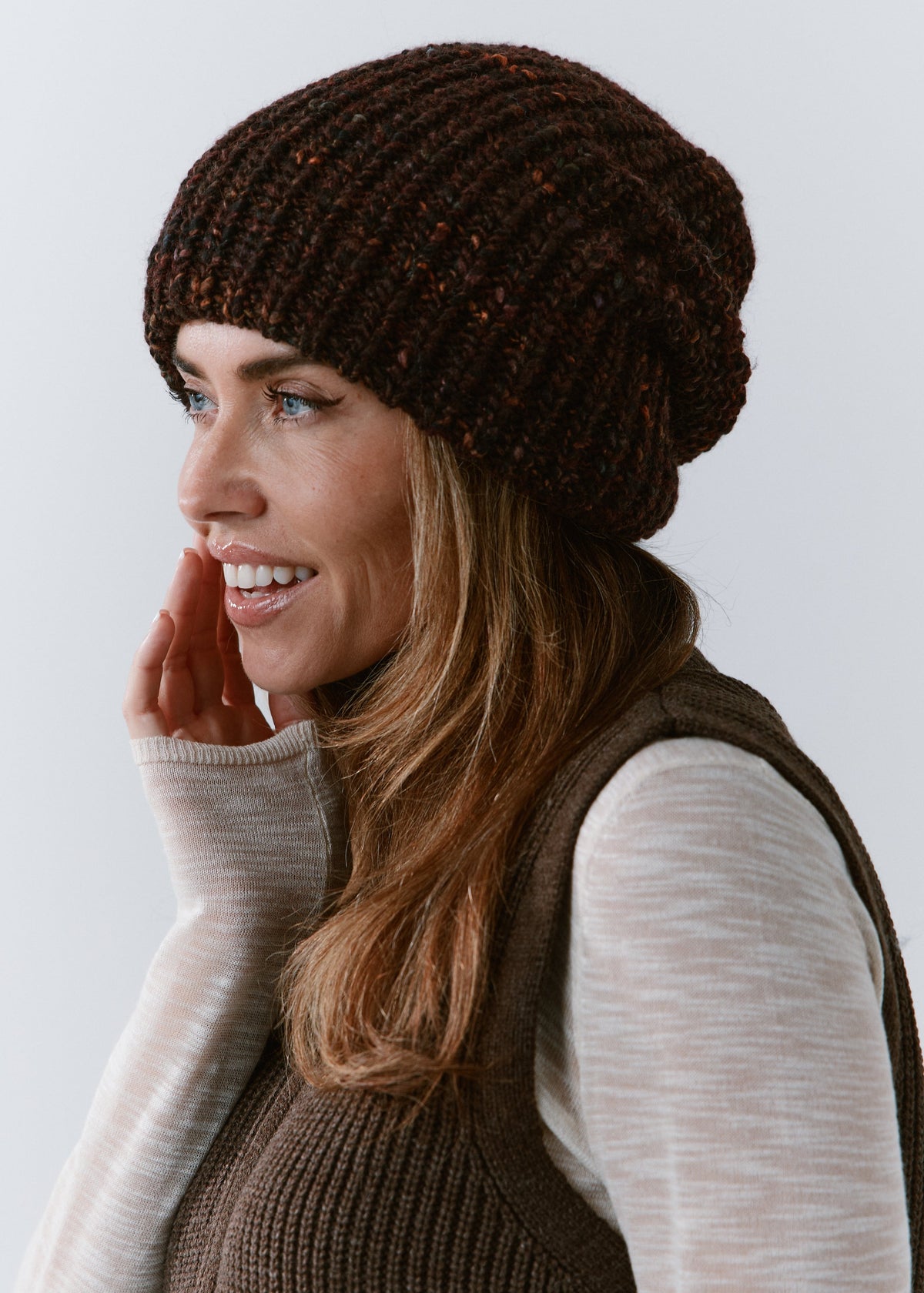 London Burgundy and Black knit beanie: Side portrait with a hand beside the face