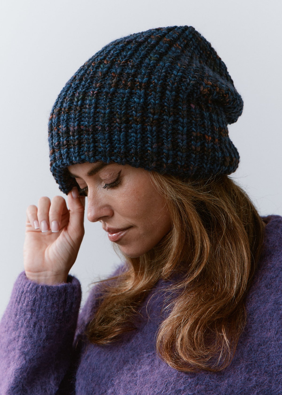 London Dark Lavender knit beanie: Looking-down portrait with a hand at the brim