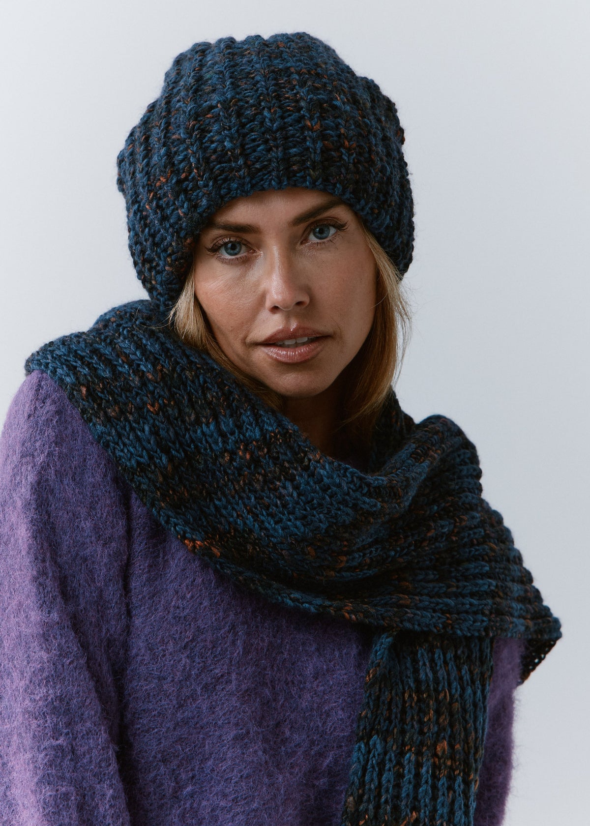 BRIKOLY Dark Lavender ribbed knit scarf in dark blue multicolor yarn, wrapped around a model's neck in a close front view.