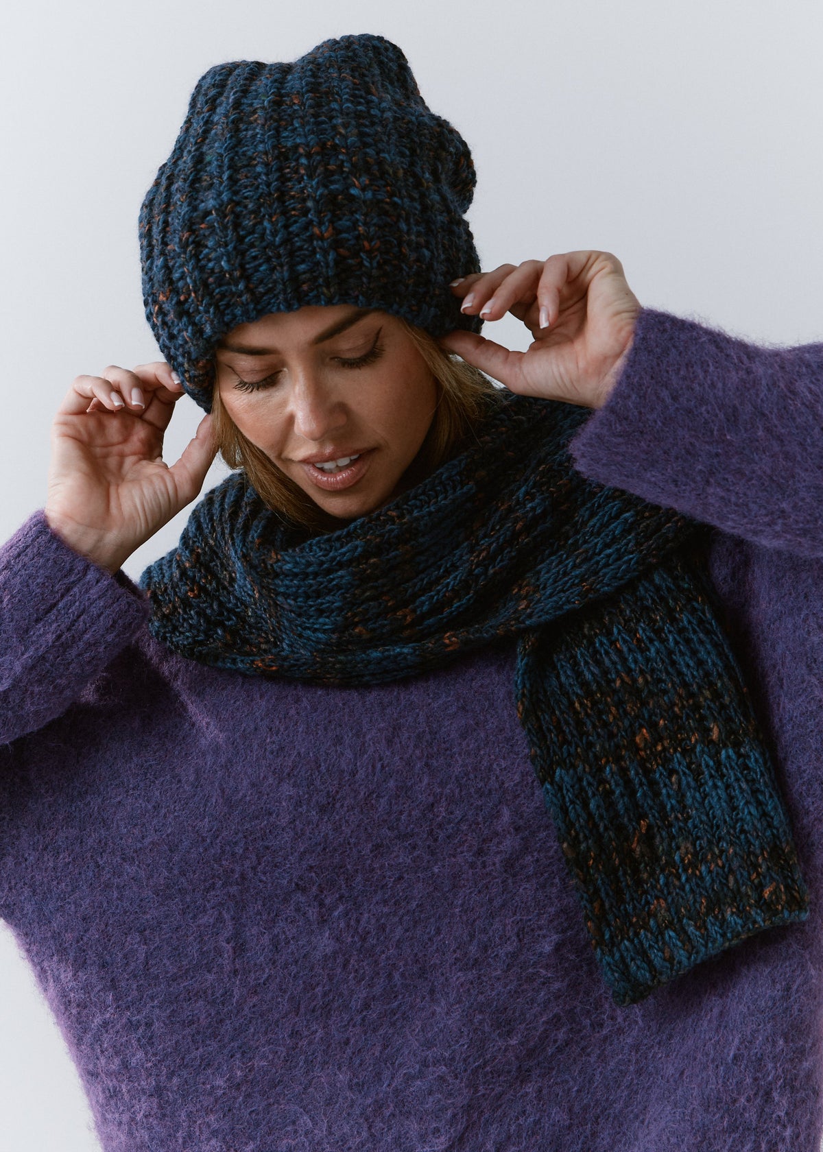 BRIKOLY Dark Lavender ribbed knit scarf in dark blue multicolor yarn, worn by a model looking down, with one ribbed end hanging in front.