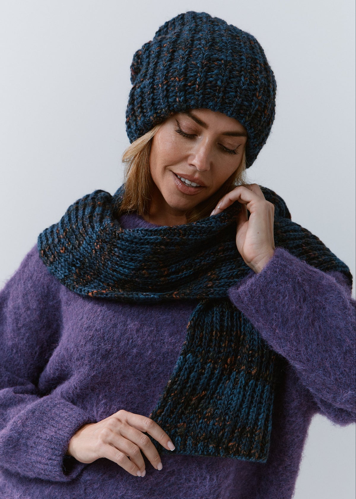 BRIKOLY Dark Lavender ribbed knit scarf in dark blue multicolor yarn, worn by a model looking down, showing the wide ribbed end.