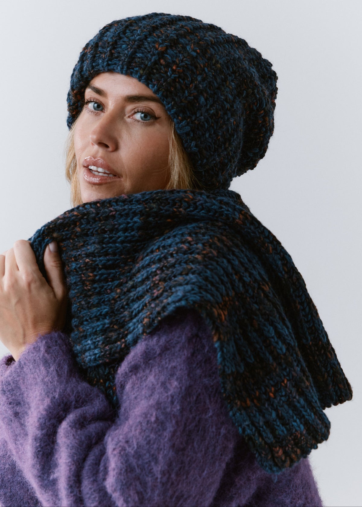 BRIKOLY Dark Lavender ribbed knit scarf in dark blue multicolor yarn, wrapped across a model's shoulders in a rear three-quarter view.