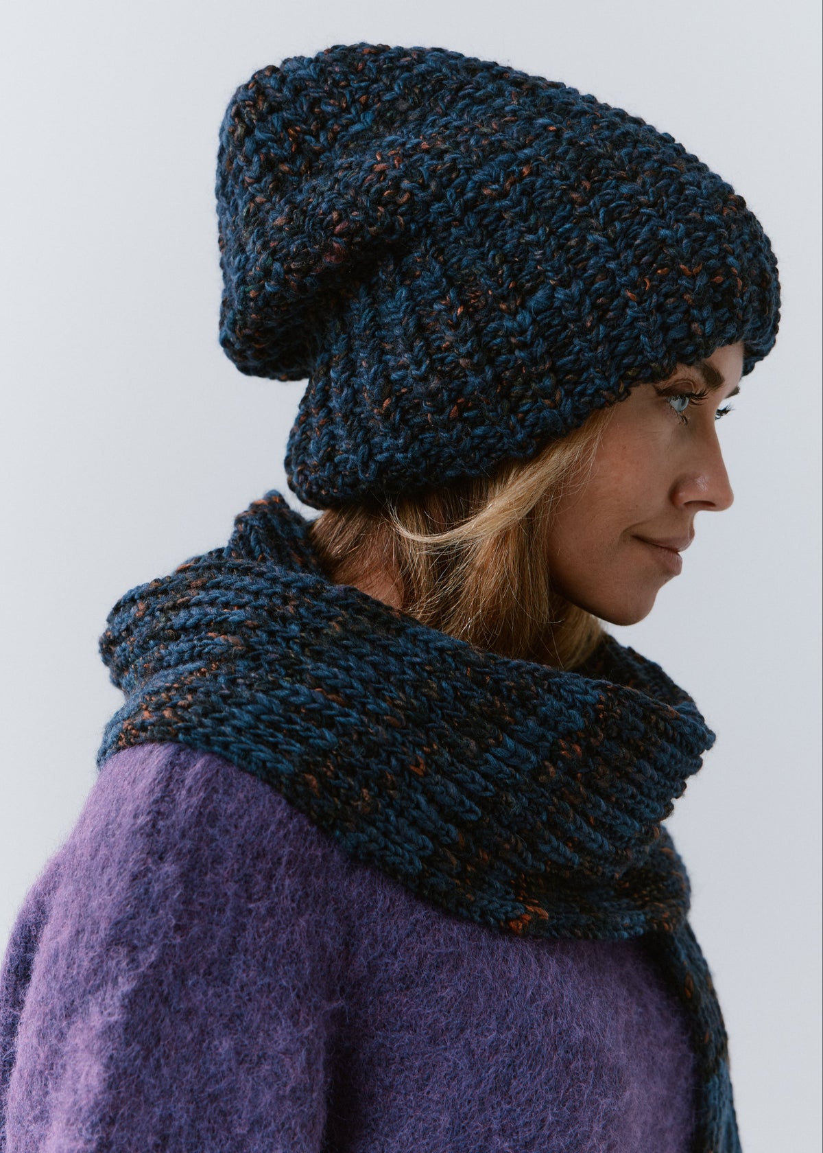BRIKOLY Dark Lavender ribbed knit scarf in dark blue multicolor yarn, shown around a model's neck in profile.
