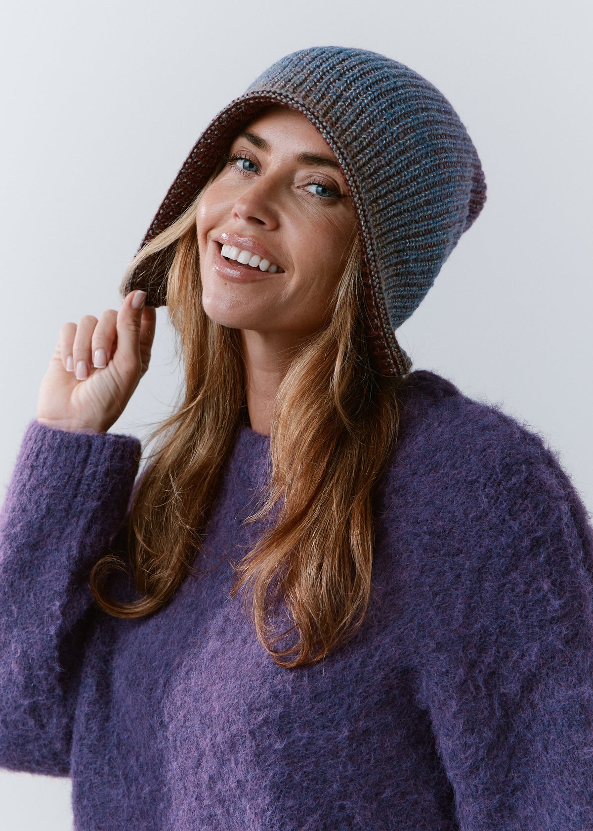 BRIKOLY Lisse Violet reversible ribbed knit beanie shown on a smiling model in a side view.