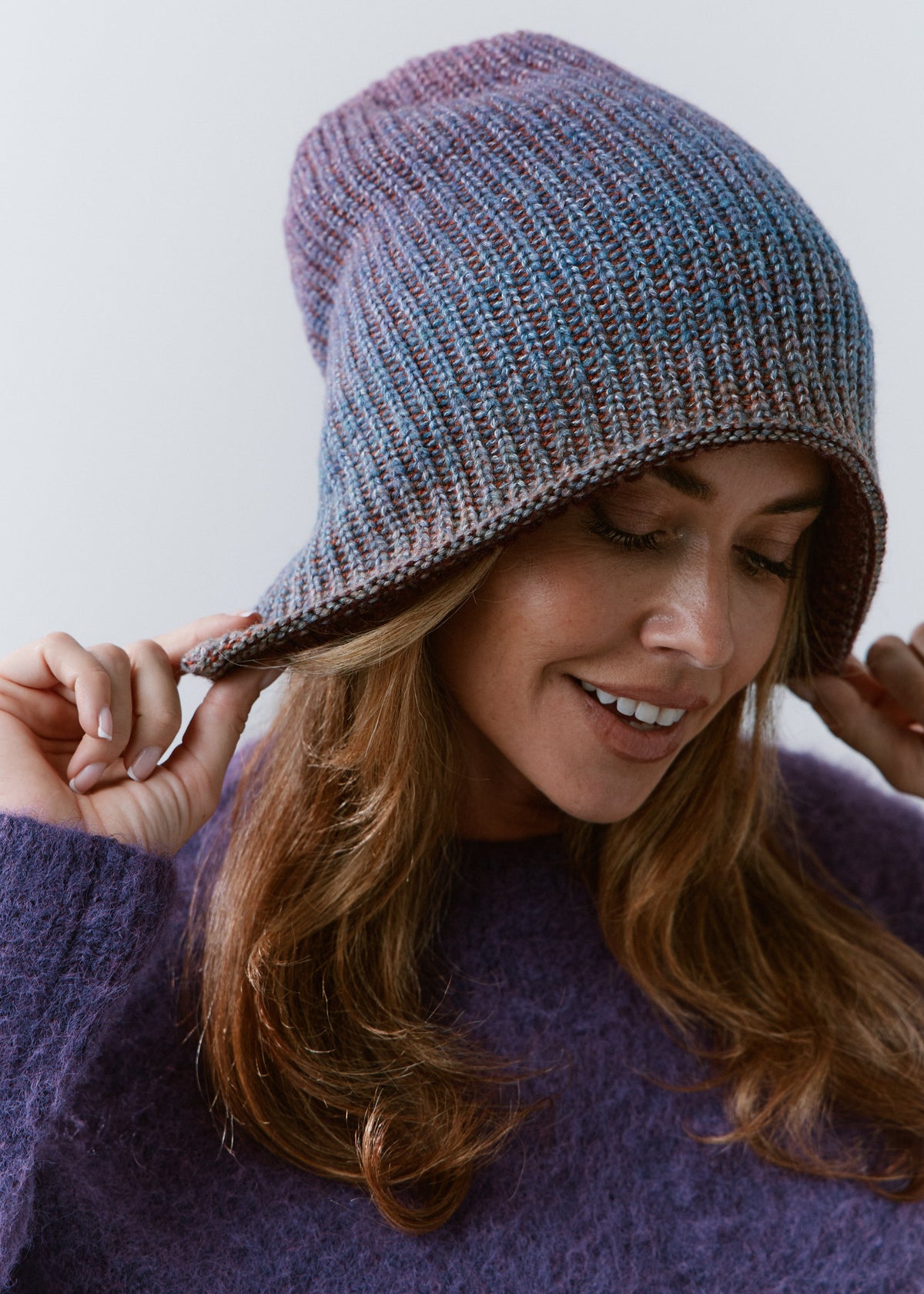 BRIKOLY Lisse Violet reversible ribbed knit beanie worn by a smiling model adjusting the brim.