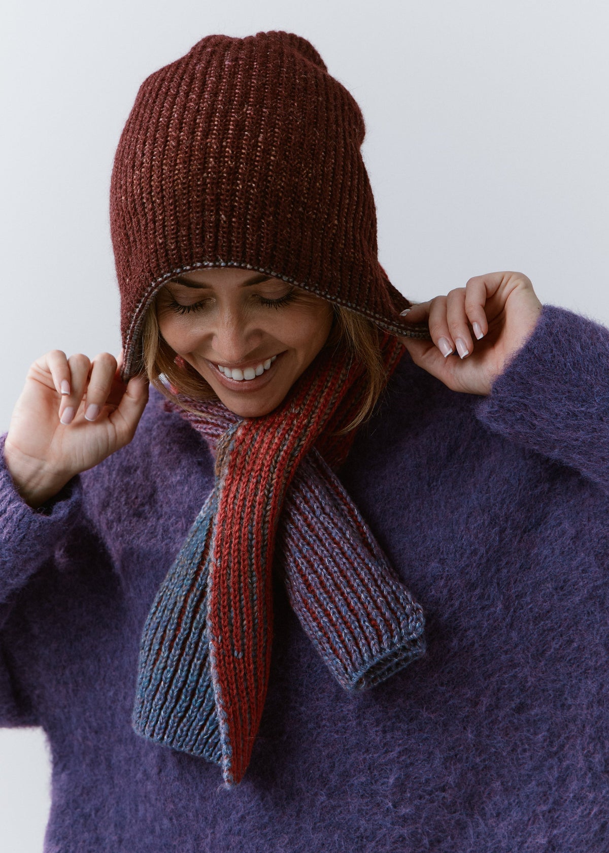 BRIKOLY Lisse Violet multicolor ribbed knit scarf secured around a model's neck with a burgundy beanie.