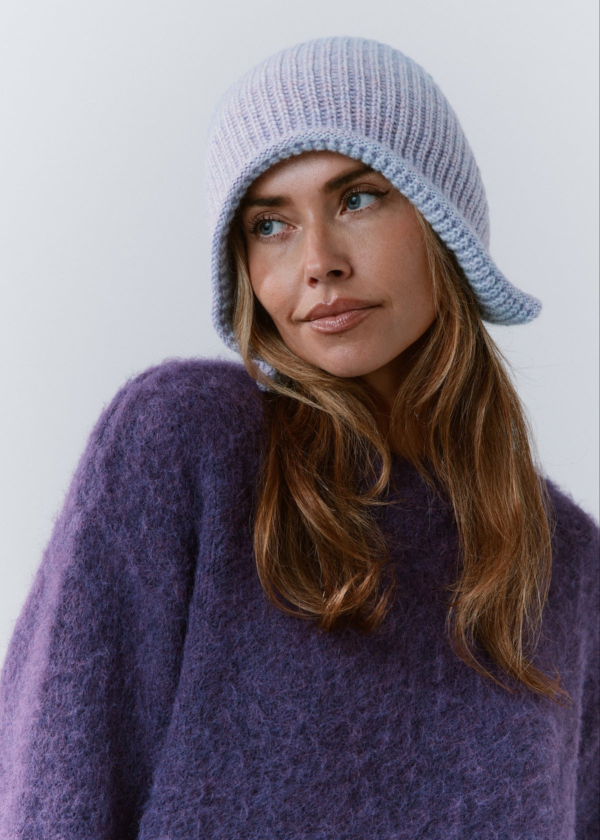 BRIKOLY Lisse Pink reversible knit beanie in pale blue and lilac tones, shown in a front view on a model looking to the side.