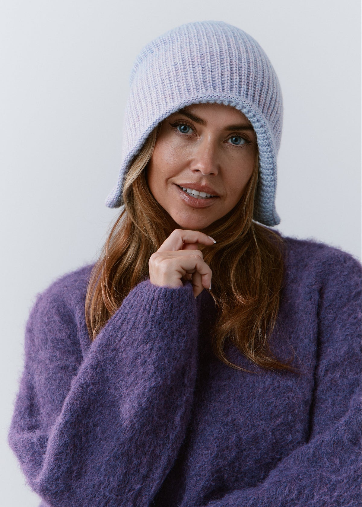 BRIKOLY Lisse Pink reversible knit beanie in pale blue and lilac tones, worn by a model over a purple sweater.