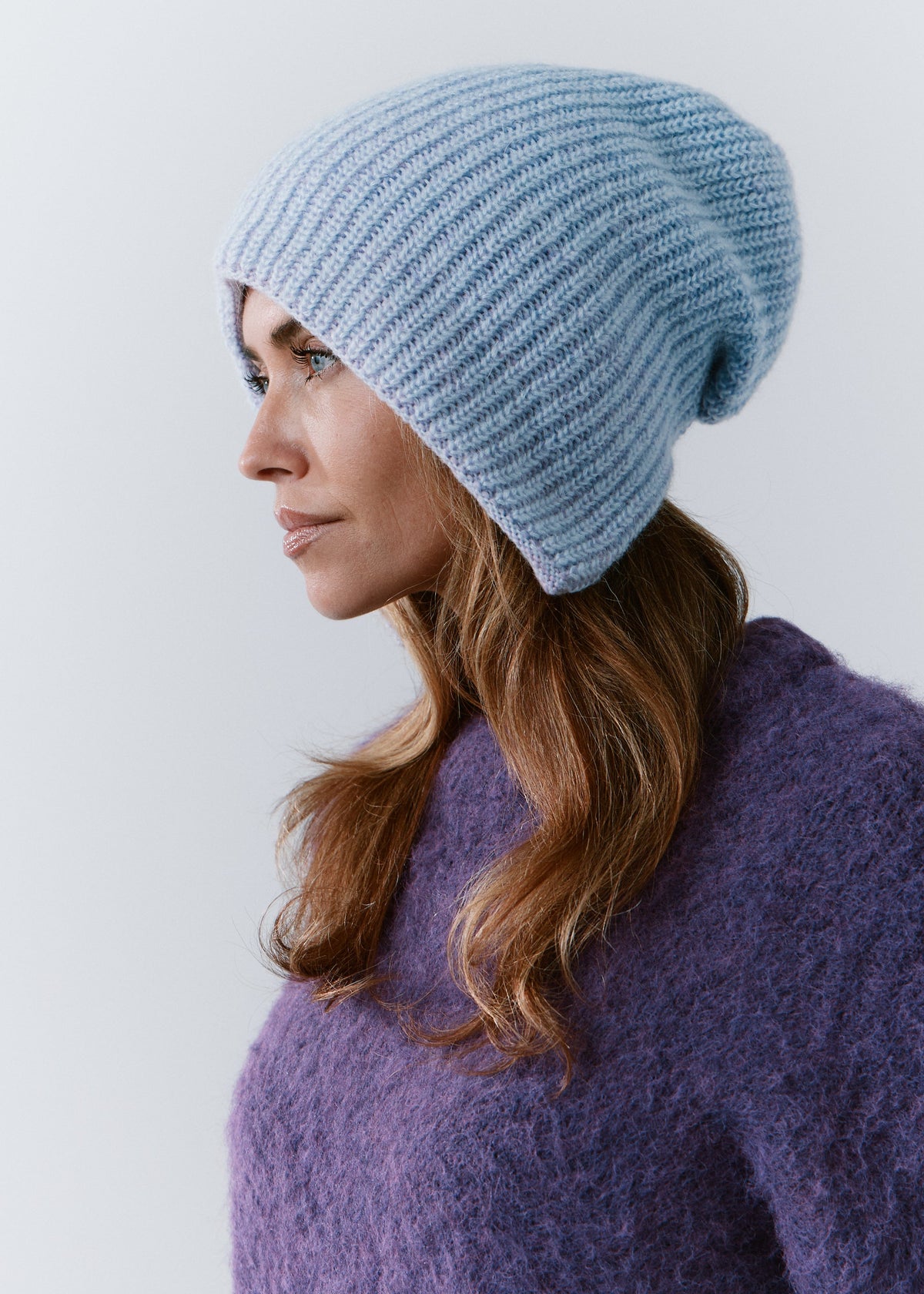 BRIKOLY Lisse Pink reversible knit beanie in pale blue and lilac tones, shown on a model looking to the side.