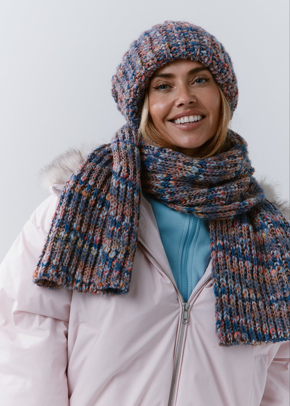 BRIKOLY Pink Blue wool and alpaca blend scarf worn over a light pink winter jacket.