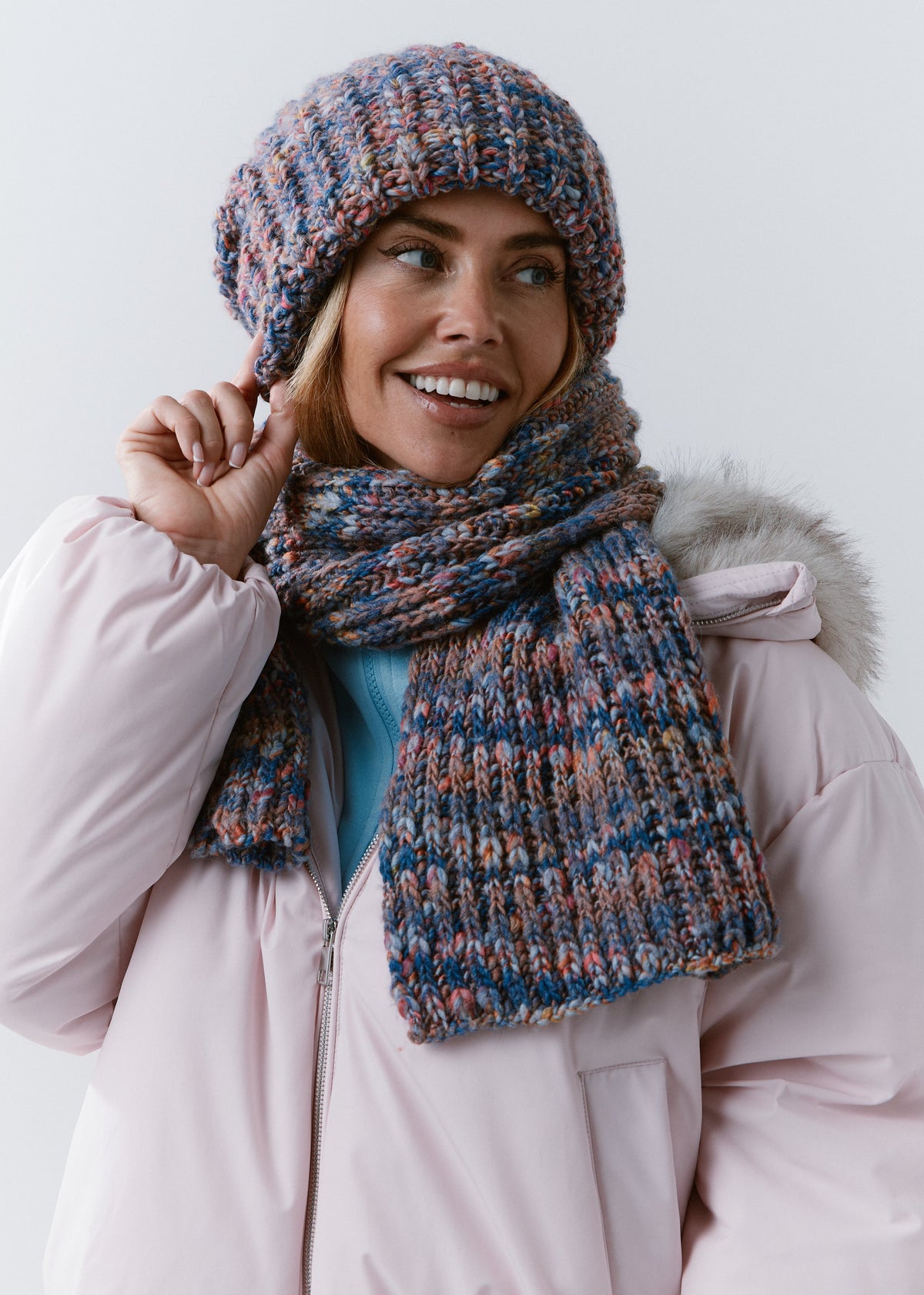 Model wearing the BRIKOLY Pink Blue scarf with a matching knit beanie, looking to the side.