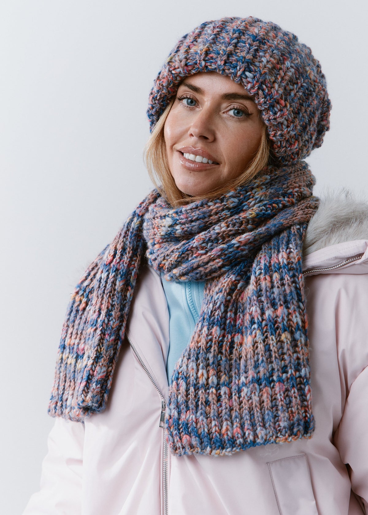 Three-quarter view of the BRIKOLY Pink Blue scarf with both ends hanging over the front of a jacket.
