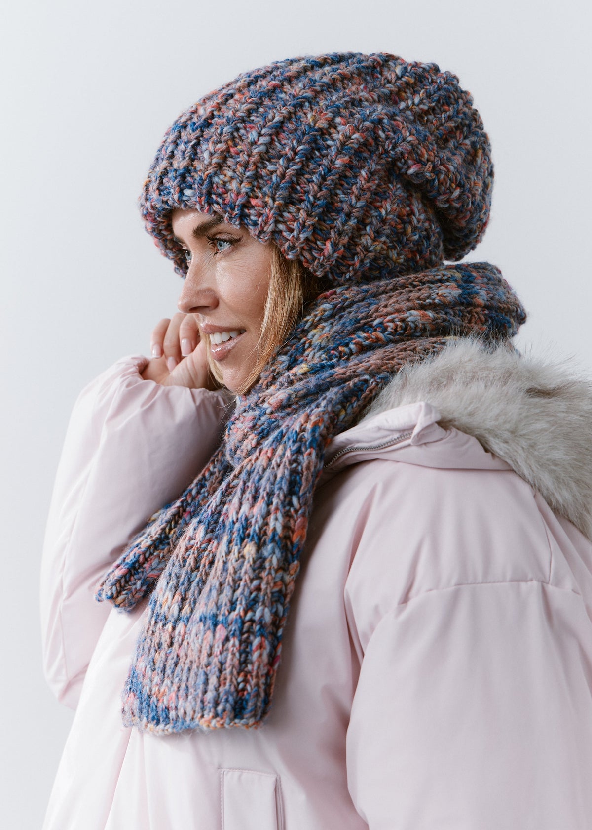 Side view of the BRIKOLY Pink Blue knit scarf wrapped around the neck with one end in front.