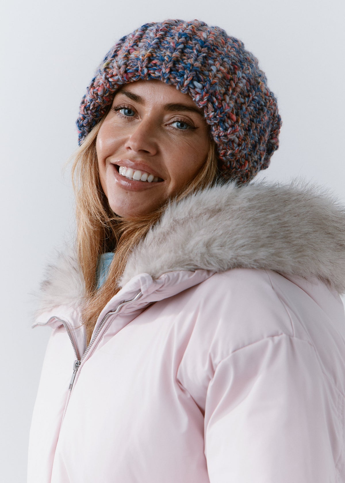 BRIKOLY Pink Blue oversized multicolor knit beanie worn by a smiling model in a three-quarter view.