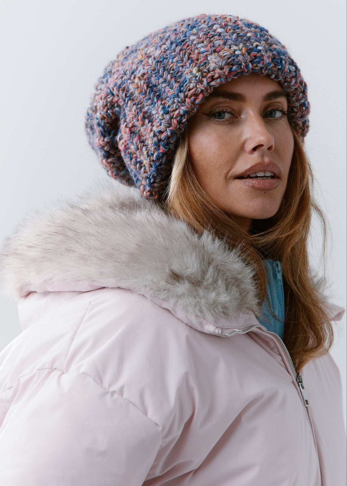 BRIKOLY Pink Blue oversized multicolor knit beanie shown in a side view on a model wearing a light pink jacket.