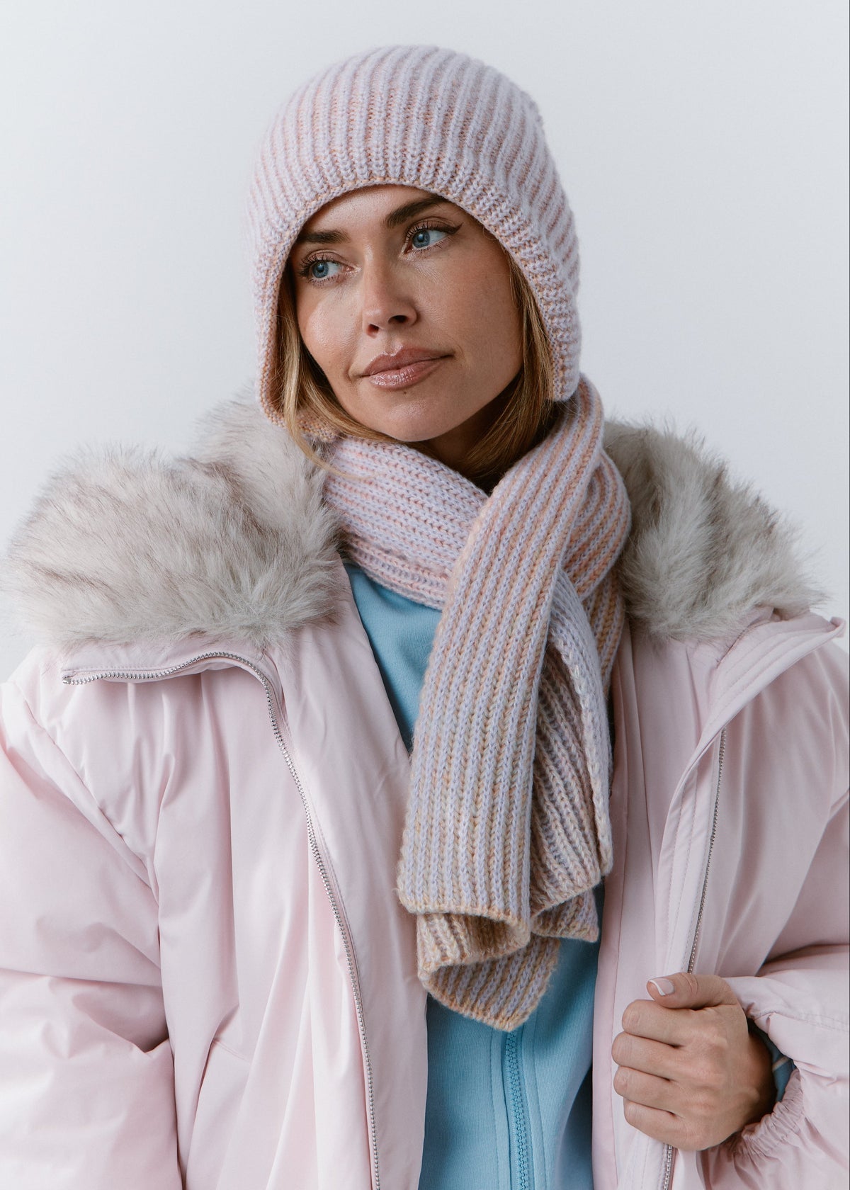 BRIKOLY Lisse Unicorn pale multicolor ribbed knit scarf wrapped around a model's neck over a pink winter jacket.