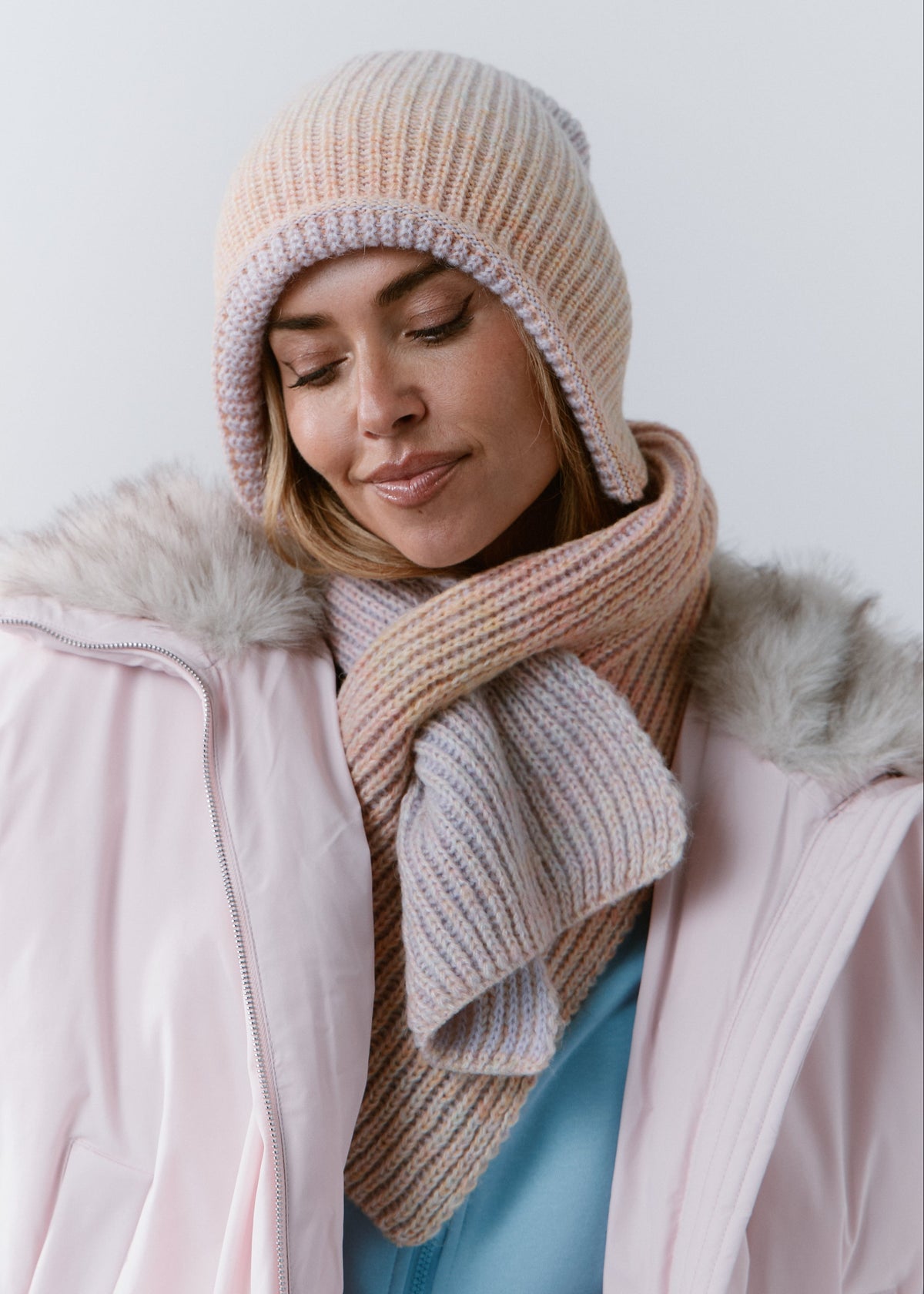 BRIKOLY Lisse Unicorn pale multicolor ribbed knit scarf secured around a model's neck, showing pale peach and lilac tones.