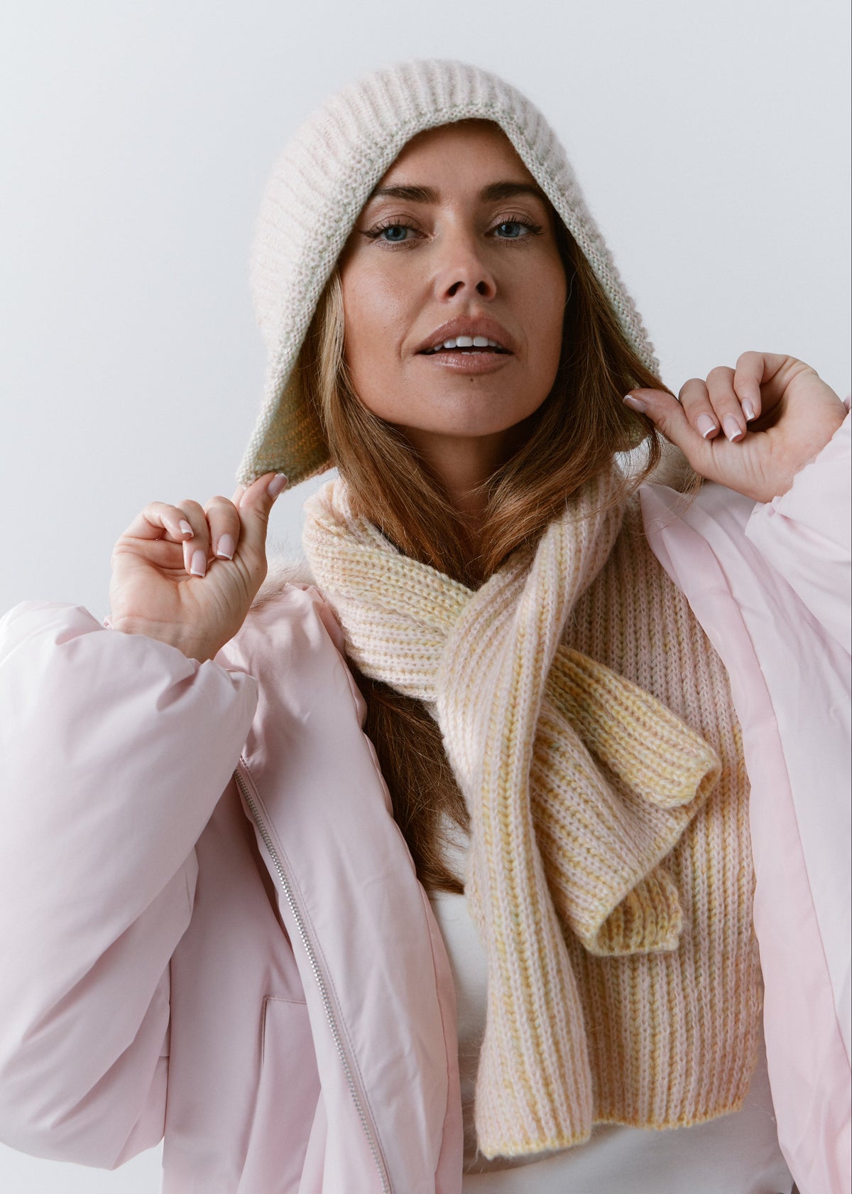 BRIKOLY Lisse Multicolor pale ribbed knit scarf secured around a model's neck over a pink jacket.