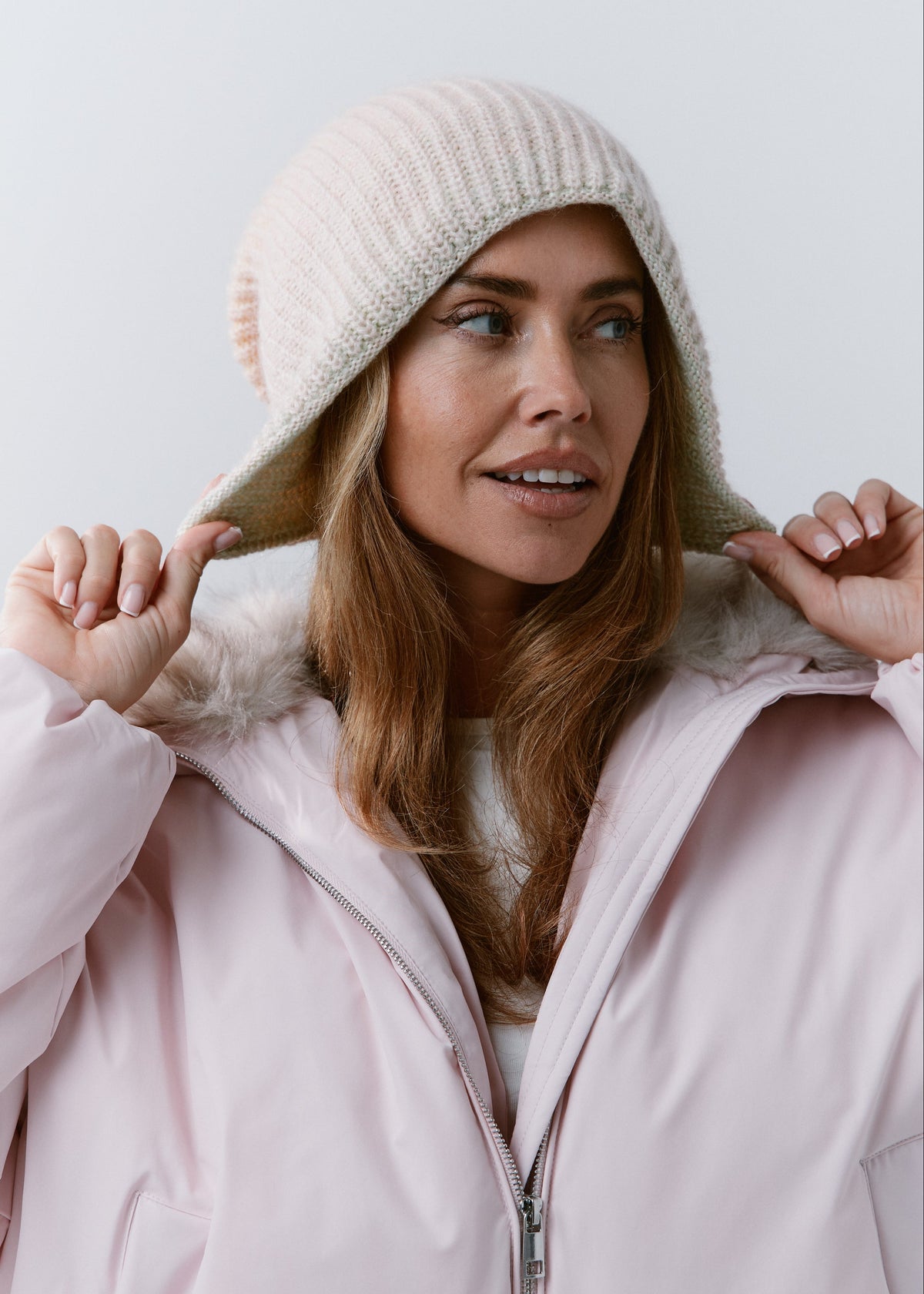 BRIKOLY Lisse Multi reversible ribbed knit beanie worn by a model adjusting the brim over a pink jacket.