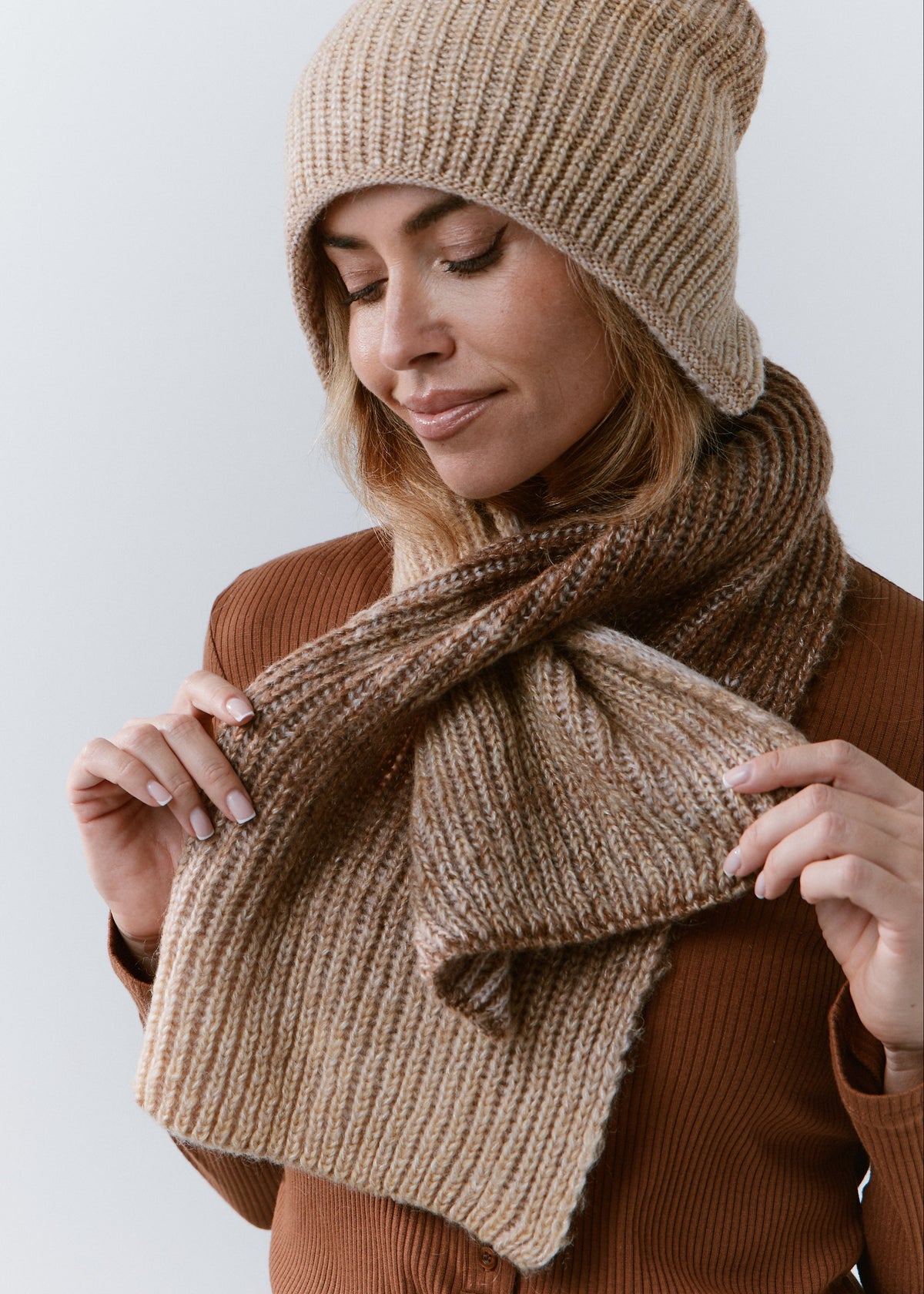 BRIKOLY Lisse Brown ribbed knit scarf held by a model looking down to show its loop styling.