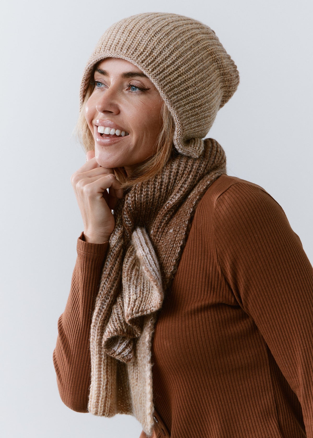 BRIKOLY Lisse Brown ribbed knit scarf worn by a smiling model in a side view.