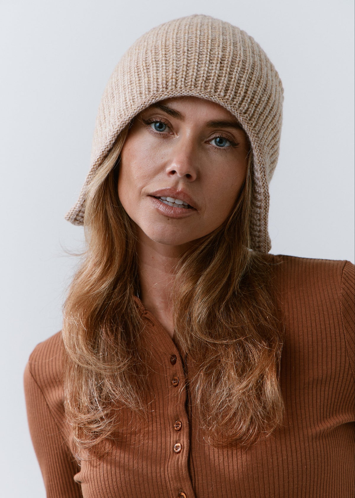 BRIKOLY Lisse Brown reversible ribbed knit beanie shown in a front view on a model wearing a brown top.