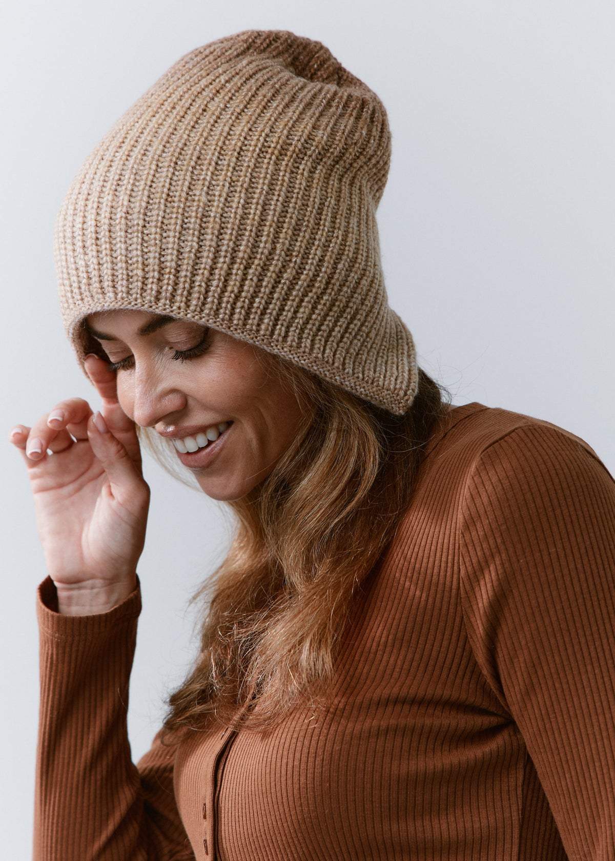 BRIKOLY Lisse Brown reversible ribbed knit beanie worn by a smiling model looking down.
