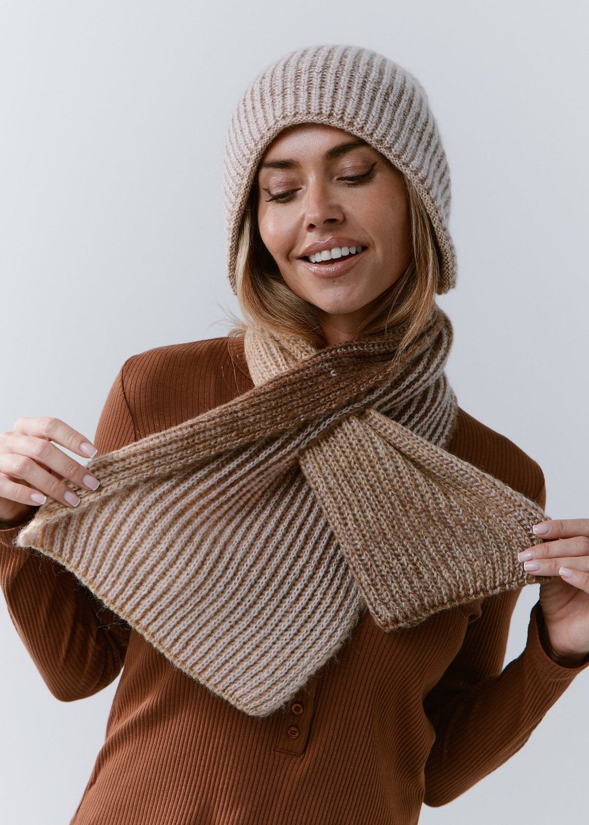 BRIKOLY Lisse Brown reversible ribbed knit beanie worn by a model holding a matching scarf in front.