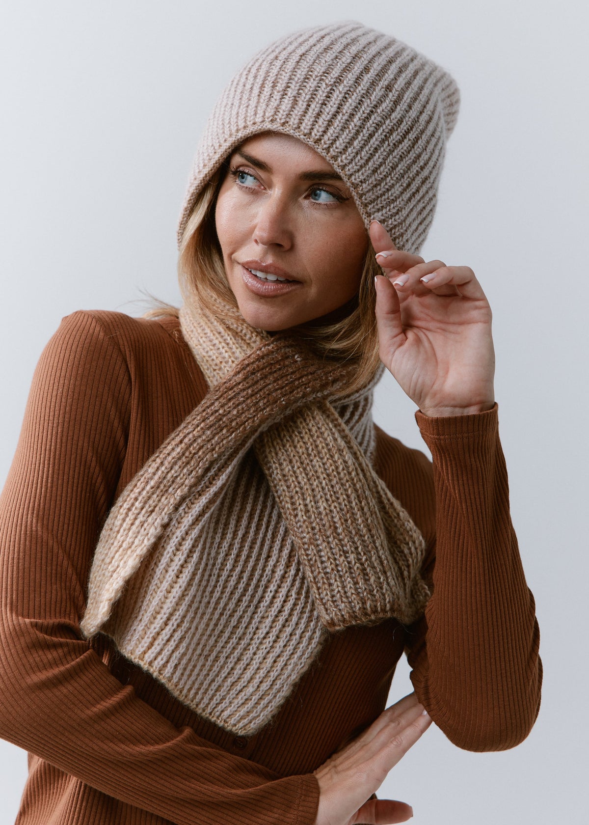 BRIKOLY Lisse Brown reversible ribbed knit beanie worn by a model adjusting the brim with a matching scarf.