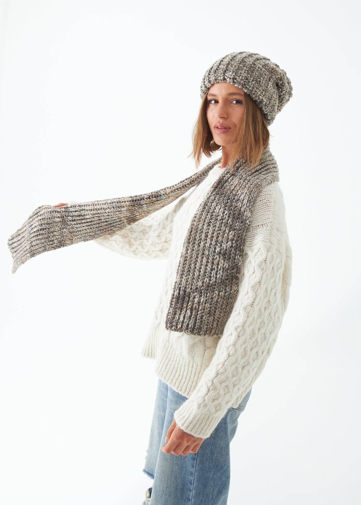 Oversized Gray alpaca-wool scarf: Three-quarter outfit view holding one end outward; beanie sold separately