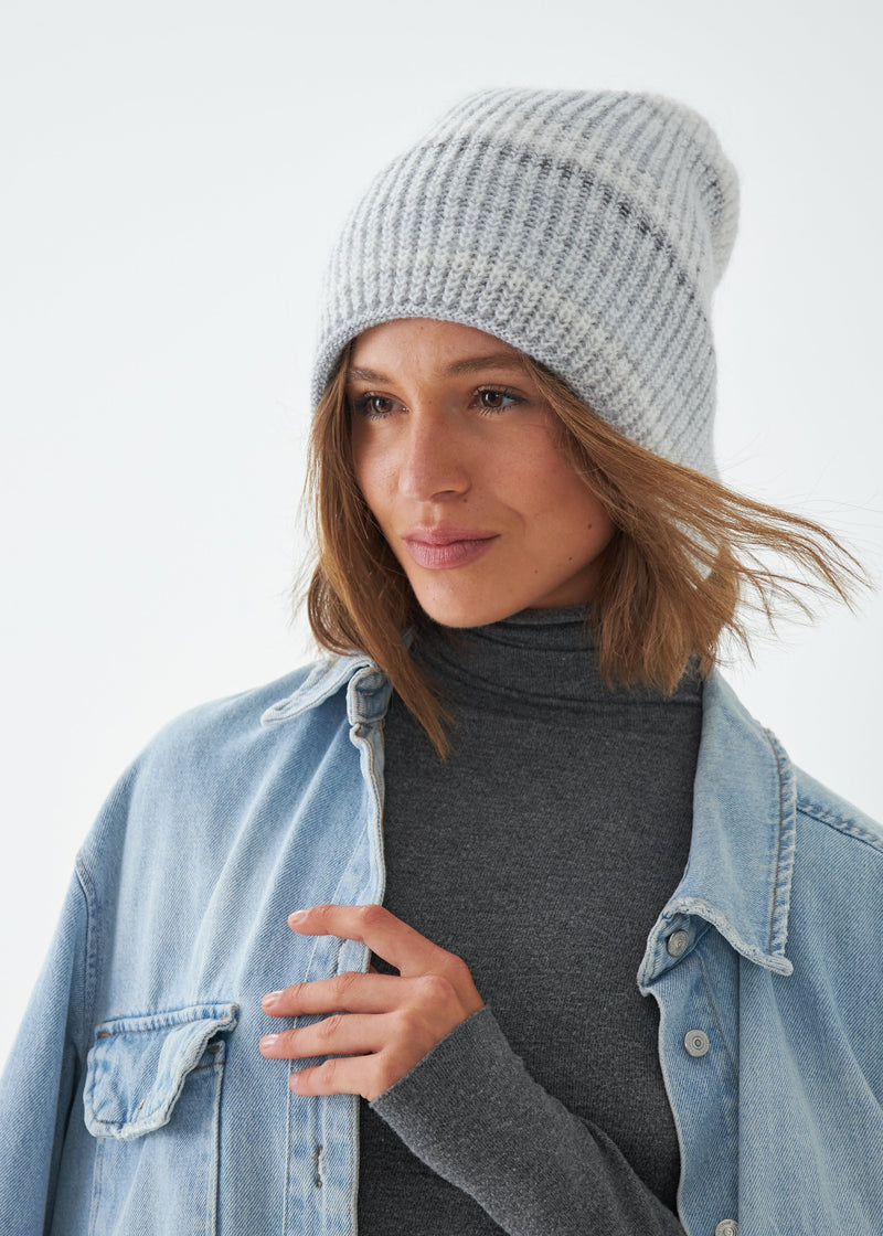 Woman wearing a gray knit beanie and denim jacket on a white background