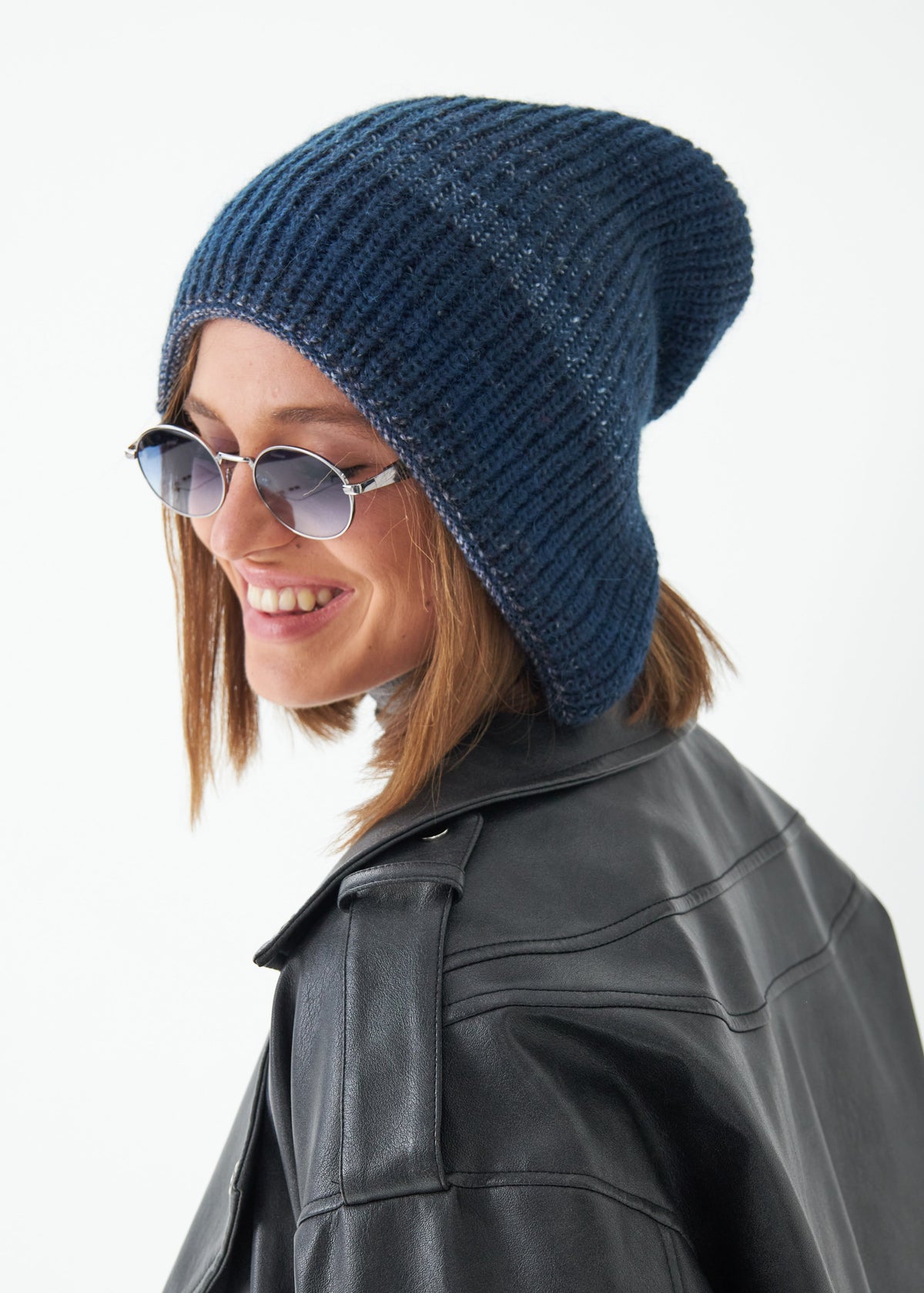 Woman wearing a blue knit beanie and sunglasses on a white background