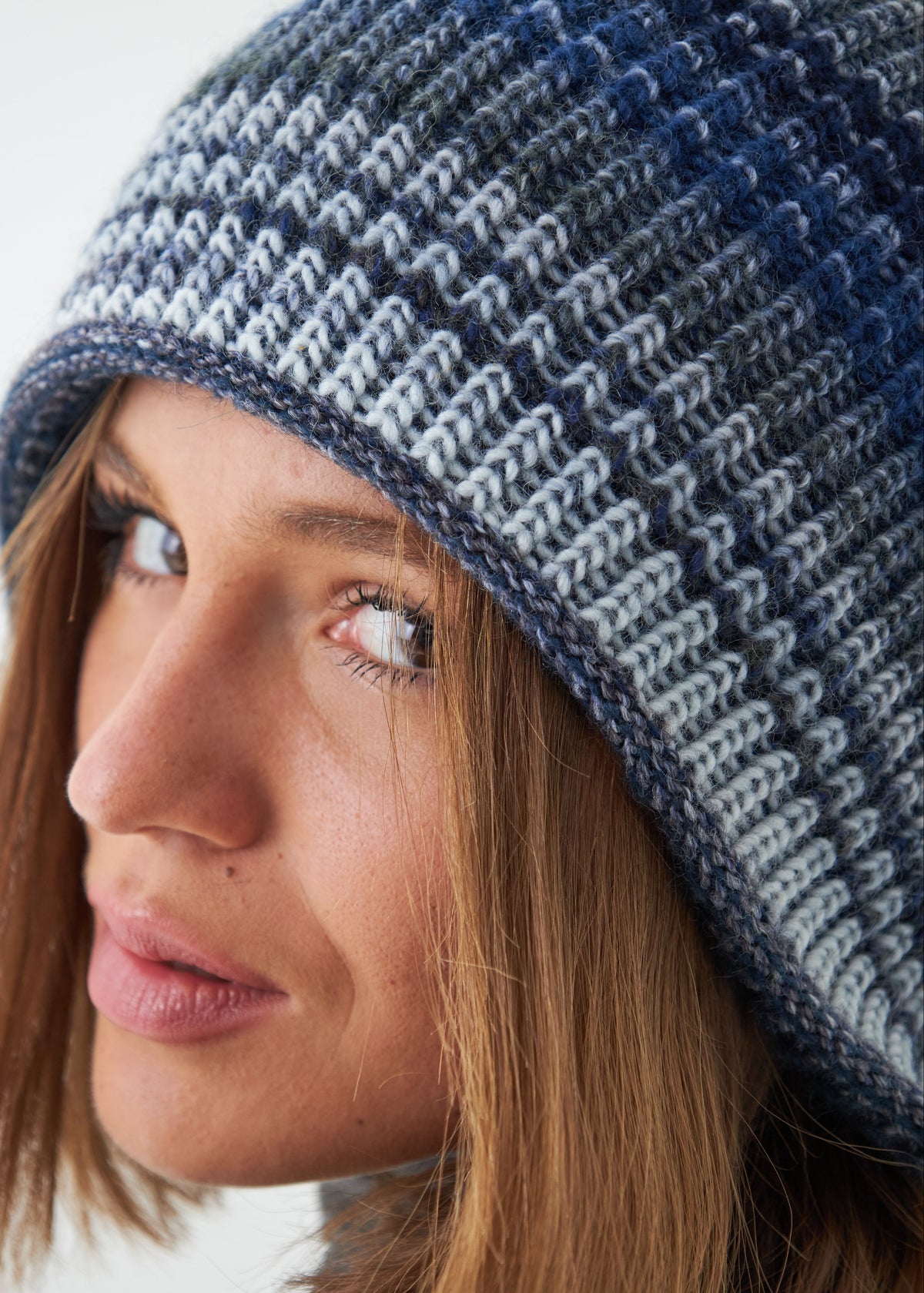 Woman wearing a blue and gray knitted beanie