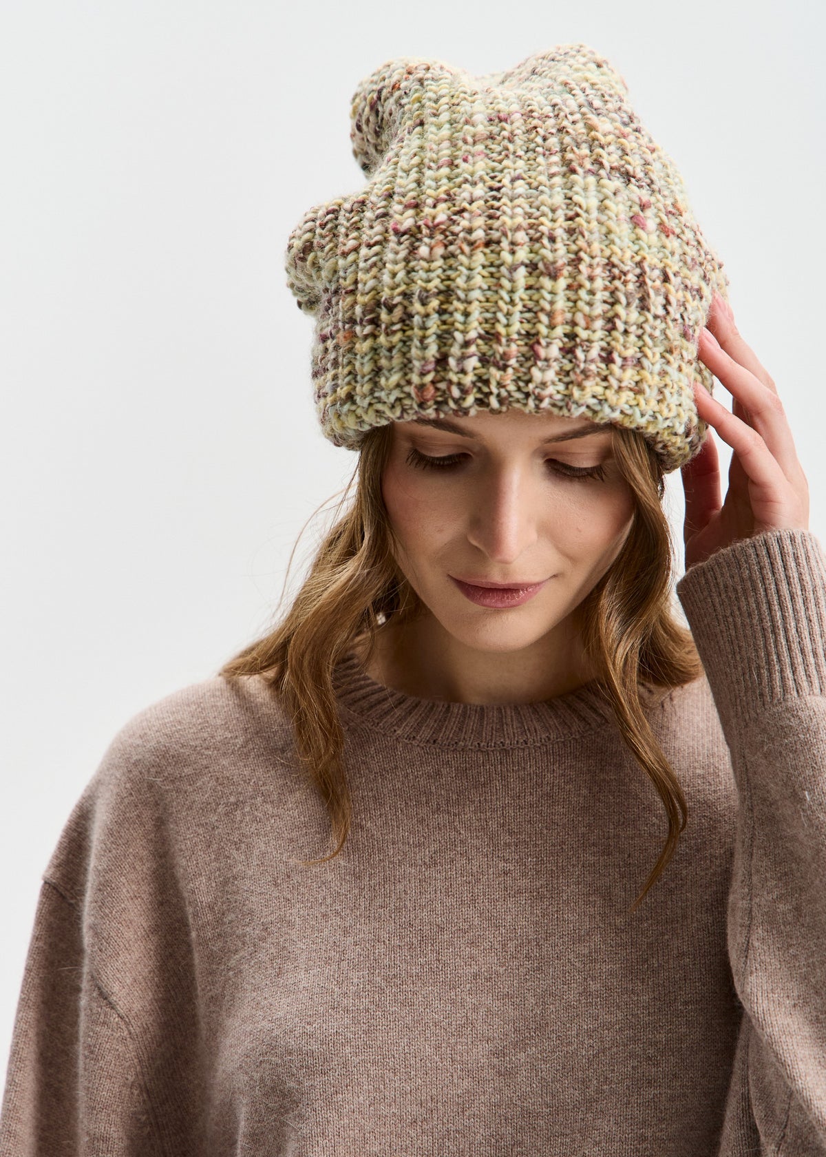 BRIKOLY London Yellow knit beanie worn by a model looking down and touching the brim.