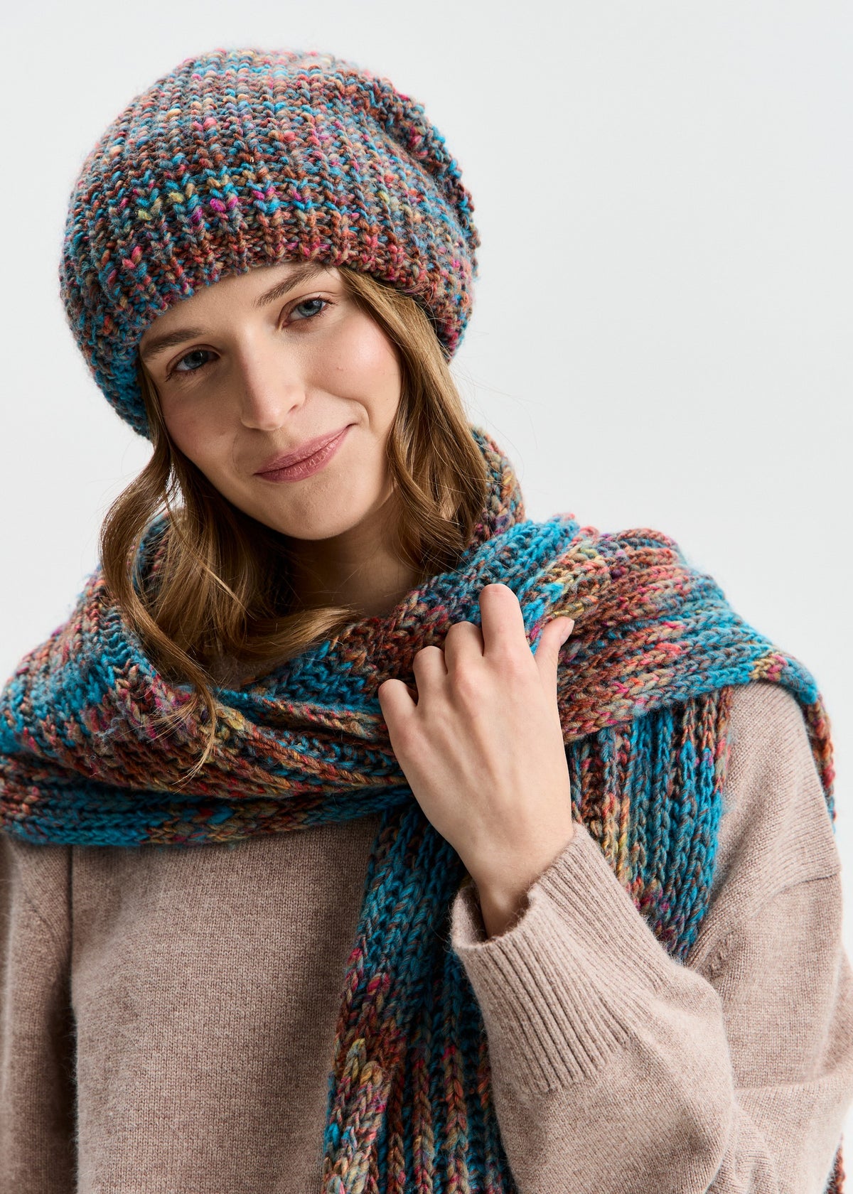 BRIKOLY London Turquoise multicolor knit beanie shown on a model holding a matching scarf.
