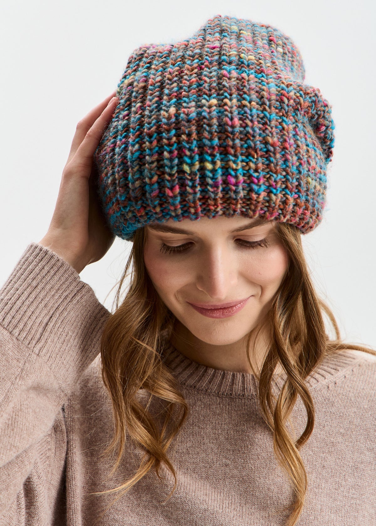BRIKOLY London Turquoise multicolor knit beanie worn by a model looking down and touching the brim.