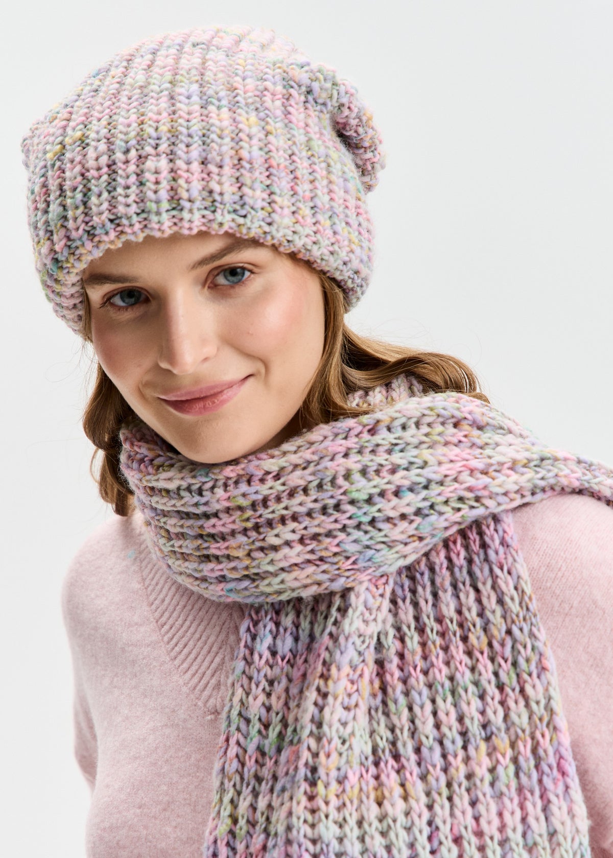BRIKOLY London Unicorn pastel multicolor knit beanie worn with a matching scarf wrapped around the neck.